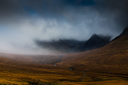 brown field near mountain surrounded by fogs thumbnail
