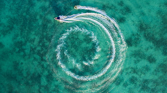 speedboat maneuvering on body of water while pulling person on wakeboard thumbnail
