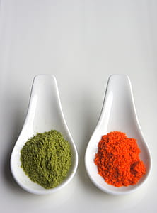 Two White Serving Spoons Filled With Condiments thumbnail