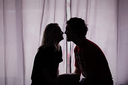 silhouette photo of man and woman about to kiss in front of curtain thumbnail