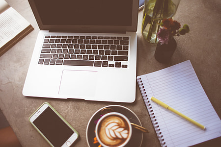 Computer, coffee, pen and notepad on a table thumbnail