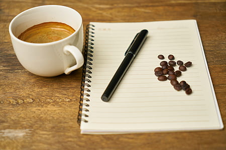 pen on top of notebook beside coffee mug thumbnail