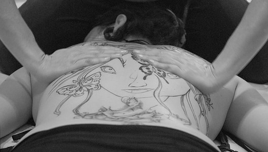 grayscale photo of person doing massage of a person lying on bed thumbnail