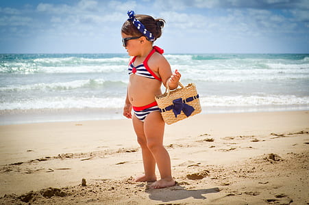 girl carrying beige wicker basket on beach shore during daytime thumbnail