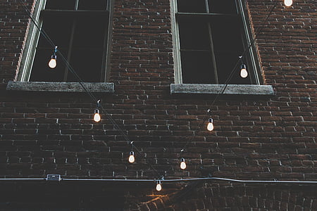 lighted string lights in front of brown brick wall thumbnail