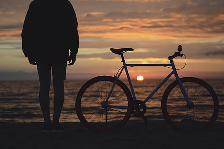 man standing bed bike on sea shore thumbnail