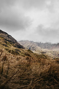 man standing on hill under cloudy skies thumbnail