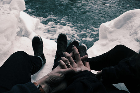 minimalist photography of man and woman holding hands together below a river thumbnail