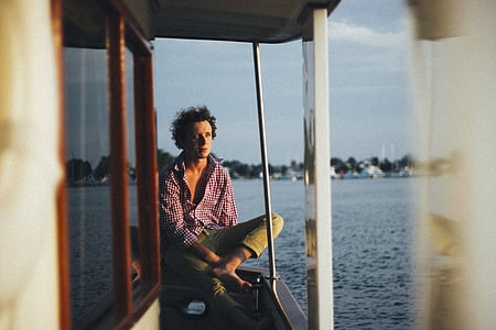 man sitting on boat railing under blue sky at daytime thumbnail