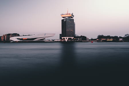 gray curtain building near calm body of water during daytime thumbnail