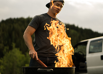 man standing in front of charcoal grill thumbnail