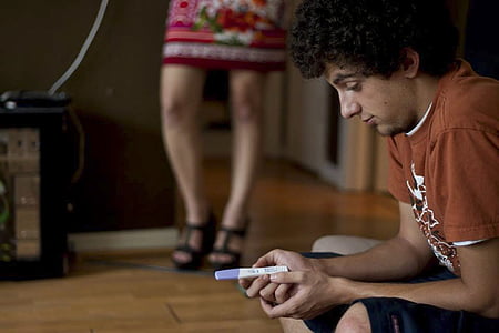 man wearing brown shirt holding pregnancy test kit thumbnail