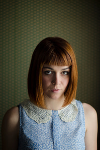 woman looking on cap with short hair near green wall thumbnail