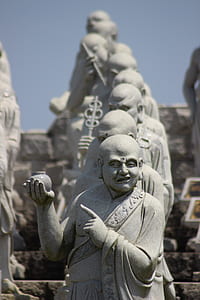 gray monk pointing finger while holding pot statue thumbnail
