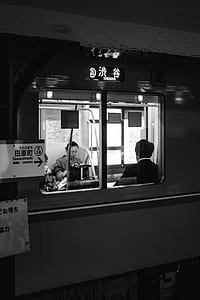 grayscale photography of man and woman sitting inside train thumbnail