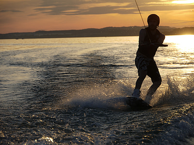 man wakeboarding on body of water during dusk thumbnail