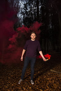 man in maroon sweatshirt and blue denim holding brown tube with red gas thumbnail