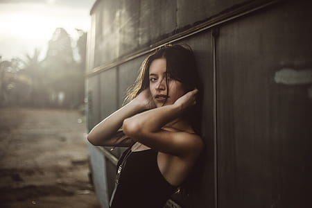 Woman in Black Spaghetti Top Holding Hair Leaning on Vehicle thumbnail