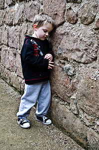 boy leaning on brown concrete wall thumbnail