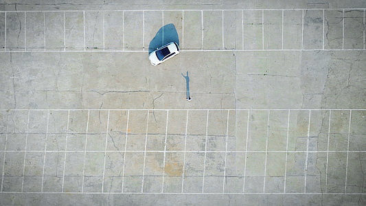 top view photo of white compact car on empty parking lot during daytime thumbnail