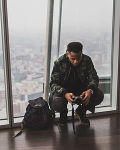 man holding DSLR camera near backpack thumbnail
