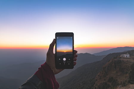 man taking photo of sun rise using smartphone thumbnail