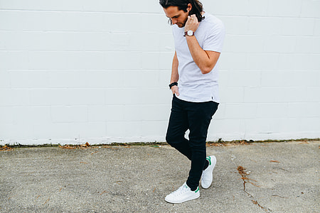 man walking near white wall thumbnail