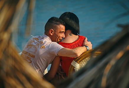 man hugging woman beside body of water thumbnail