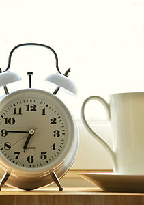 alarm clock at 6:45 time beside white mug thumbnail