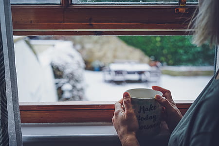 woman holding mug while facing on window thumbnail
