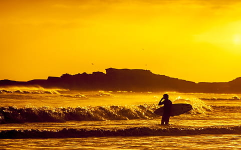 man holding surfboard during sunset thumbnail