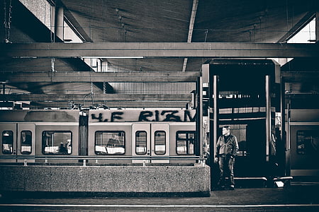 grayscale photo of man standing in front of train thumbnail