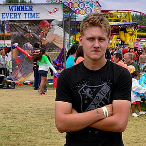 man crossing arms while standing near carnival at daytime thumbnail