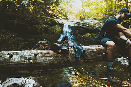 man sitting on tree trunk lying on river at daytime thumbnail