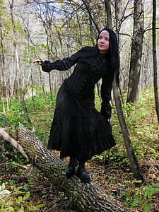 woman wearing black dress standing on brown tree log thumbnail