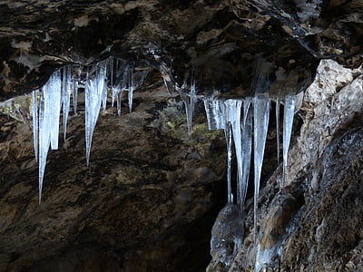 low-angle photo of stone cave with icicles on entrance thumbnail