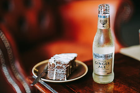 Ginger Ale bottle beside sliced cake with spoon on table thumbnail