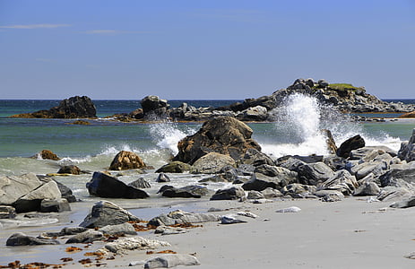 sea waves crashing on rocks under blue sky thumbnail