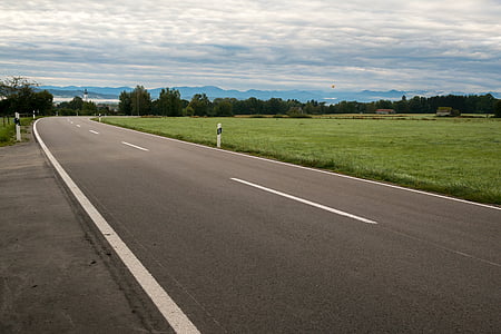 black concrete road under white cloudy sky during daytime thumbnail