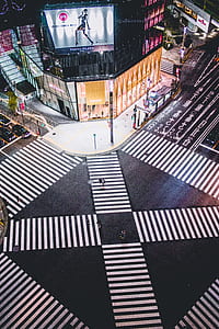 man and woman walking on pedestrian lain near lighted building photo during daytime thumbnail