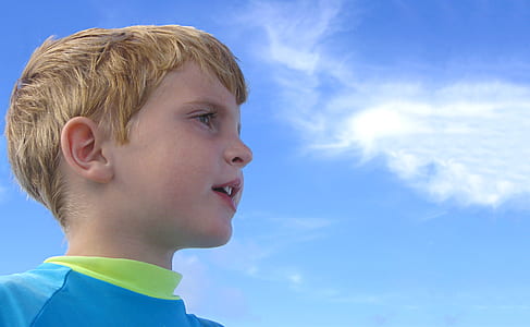 closed up photo of boy in teal and green crew-neck shirt thumbnail