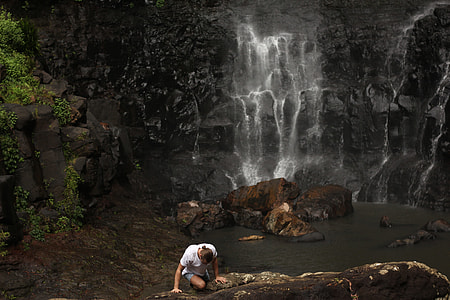 person climbing on rock near body of water thumbnail