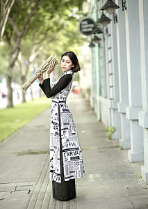 woman standing beside wall while holding grass bouquet thumbnail