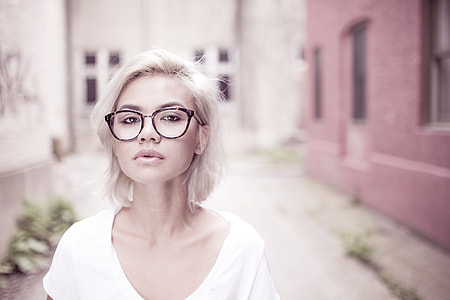 woman in white deep v-neck shirt and eyeglasses standing on pathway beside pink wall during daytime thumbnail