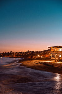 person walking on the beach in distant of buildings thumbnail