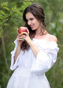 woman wearing white strapless elbow-sleeved dress holding honeycrisp apple thumbnail
