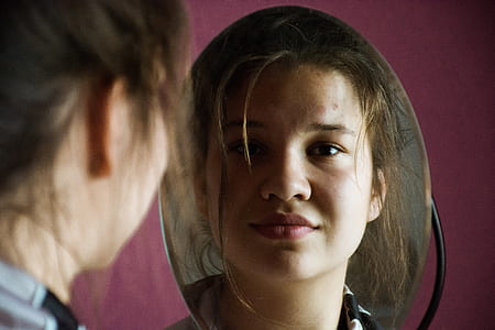 selective focus photography of woman smiling on reflection of mirror thumbnail