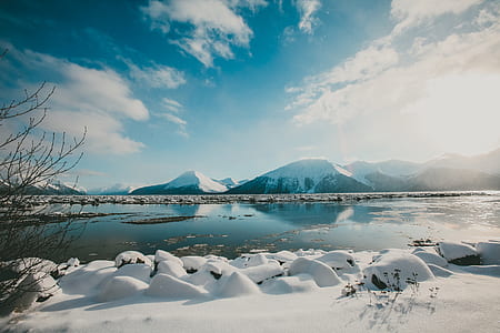 body of water and snow covered mountain under blue sky thumbnail