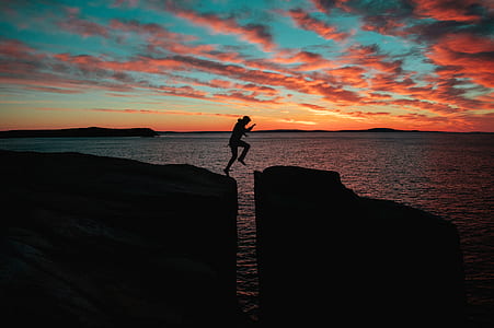 silhouette photo of person jumping on cliff thumbnail