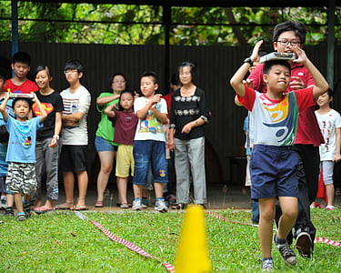 boy walking with book on his head in front of boy wearing red t-shirt during daytime thumbnail